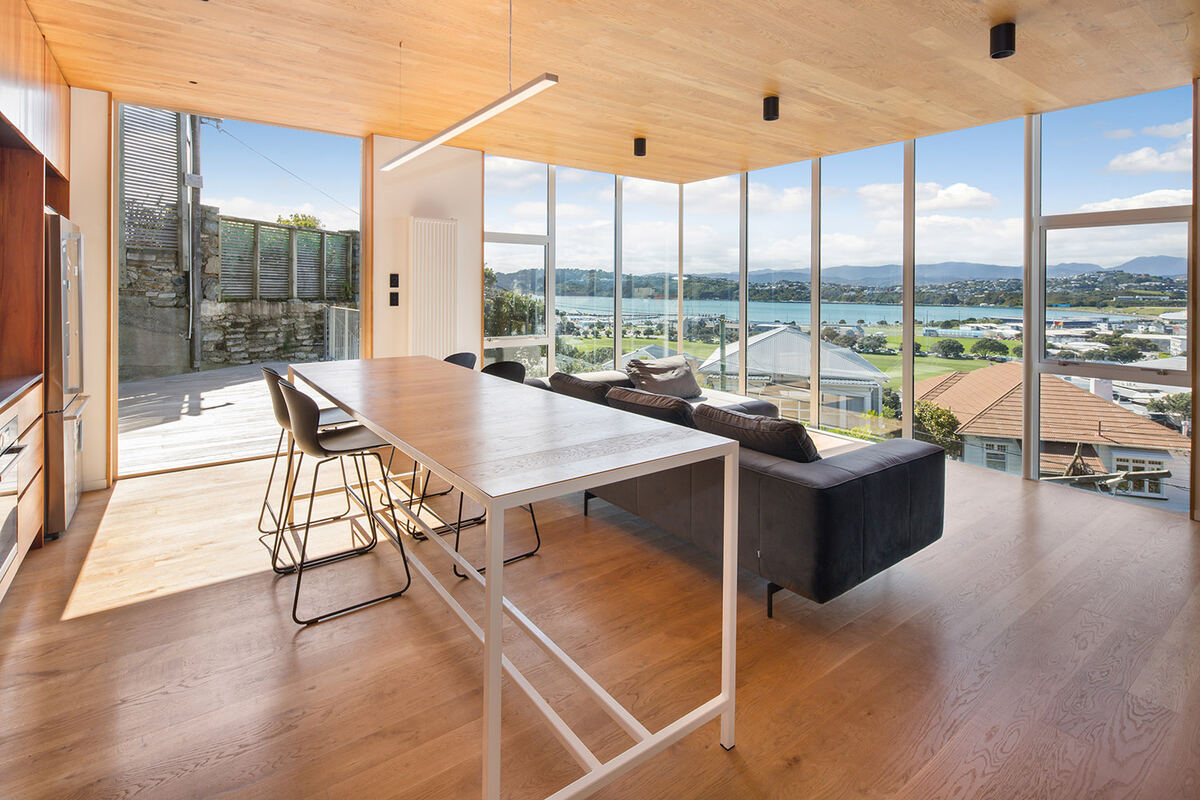 Open living and dining room with timber ceiling and harbour view