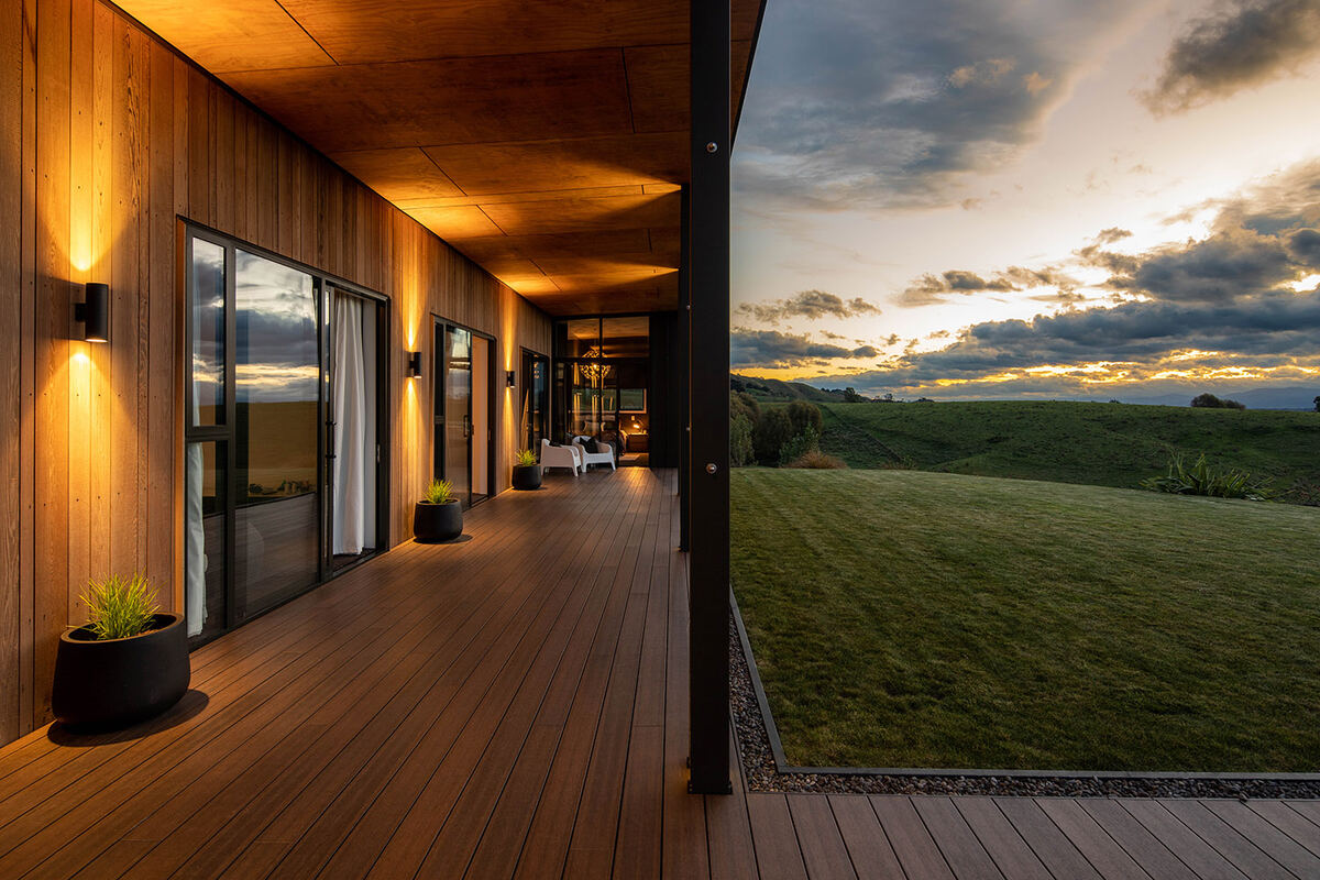 Covered deck at dusk with lit timber walls and rural outlook